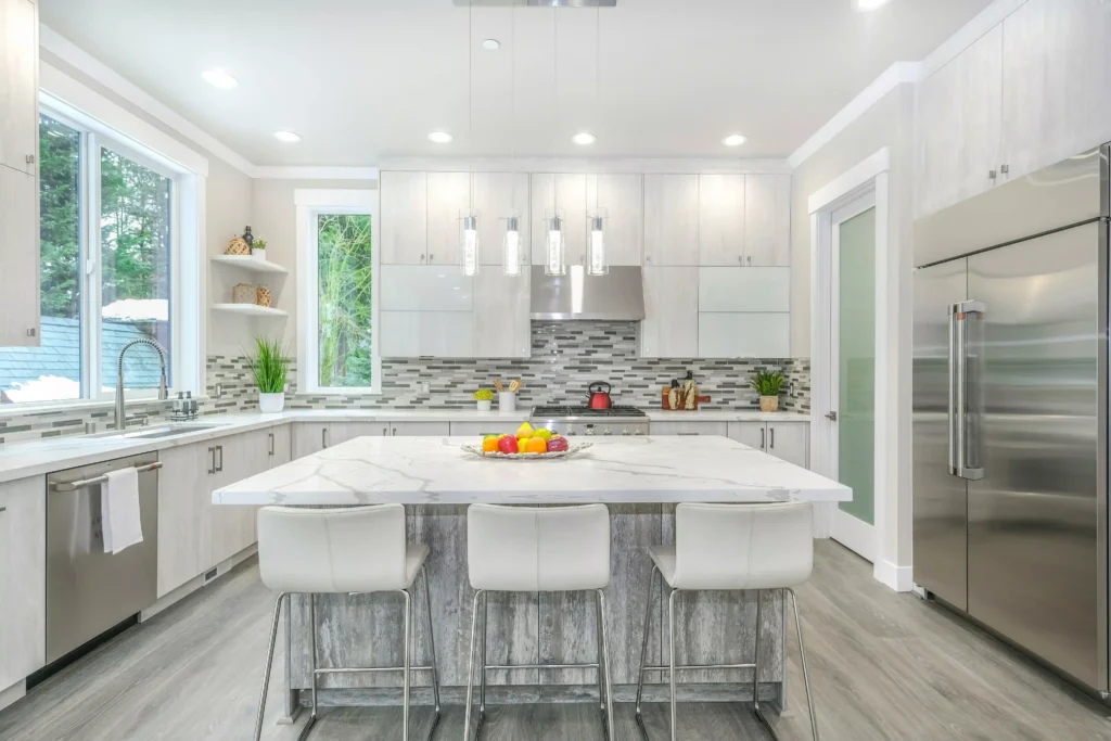 Modern kitchen with a marble island, white cabinets, stainless steel appliances, and pendant lights.
